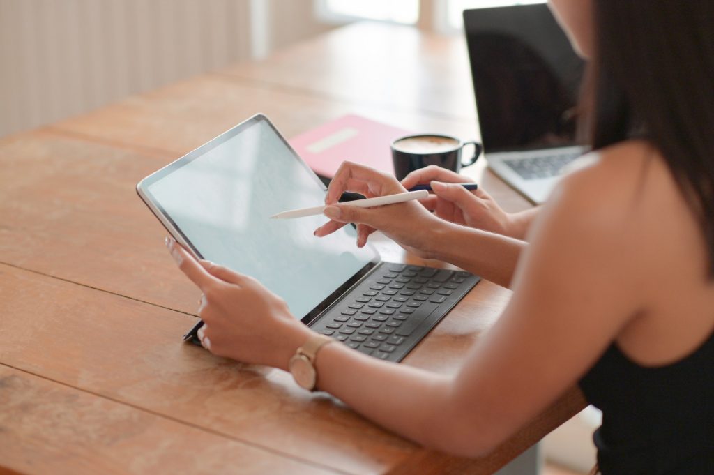 Cropped view of a young student using a pen on a tablet to present his university admission.