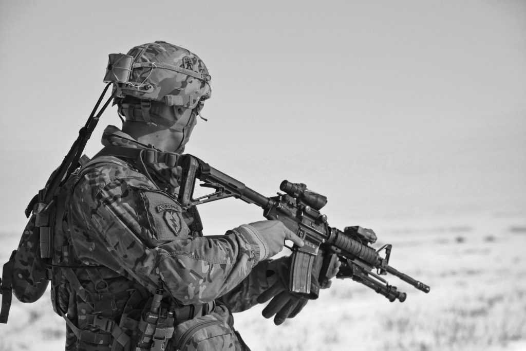 QUANDO A VIDA TE EXIGE A CORAGEM DA GUERRA PARA MANTER VIGENTE A LEI DO VENTRE LIVRE. A soldier in military gear holding a rifle, captured in black and white.