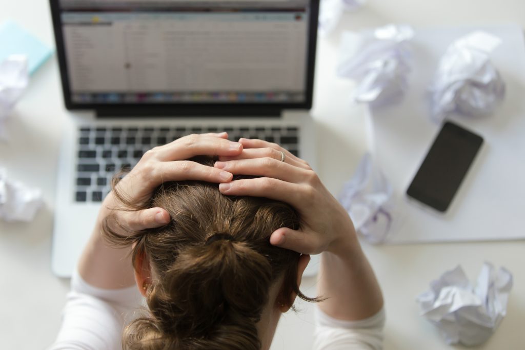 portrait of a woman grabbing head at desk near the laptop